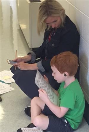 Image of a teacher and child work on reading in the hallway 
